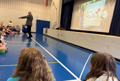  the author standing and pointing to a student in the crowd in front of the screen with his name.
